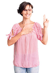 Beautiful young woman with short hair wearing casual summer clothes smiling swearing with hand on...