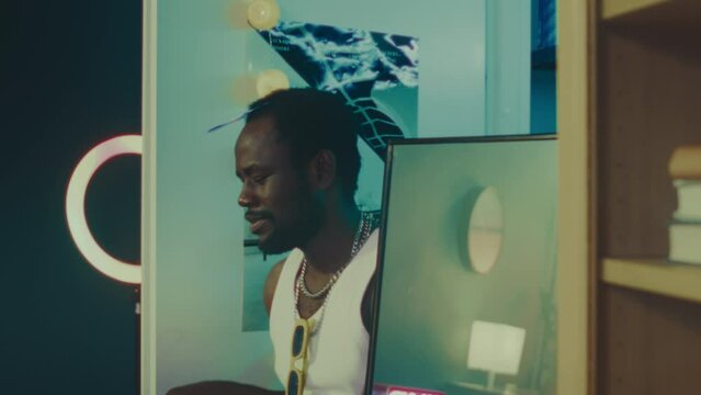 Medium slowmo of young African American hipster guy wearing white undershirt and chains making slow dancing movements in modern neon light room with little smoke