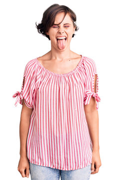 Beautiful young woman with short hair wearing casual summer clothes sticking tongue out happy with funny expression. emotion concept.