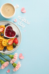 Mother's Day brunch layout: overhead vertical shot of a table with heart waffles, berries, syrup,...