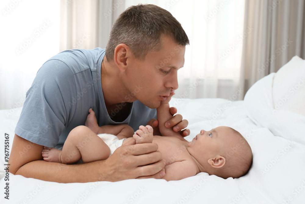 Wall mural father with his cute baby on bed at home