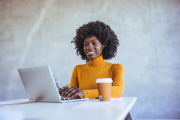 African black business woman working on laptop at office. Smiling mature african american...