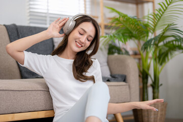 Young woman enjoying her vacation Listen to her favorite songs while relaxing in the living room at...