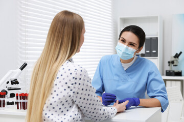 Laboratory testing. Doctor taking blood sample from patient at white table in hospital