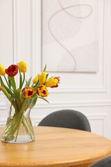 Vase with beautiful tulips on table in dining room