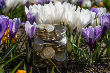 Glass jar with Kazakhstan coins in denominations of 100 and 200 tenge against a background of...