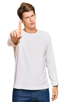 Handsome caucasian man wearing casual white sweater pointing with finger up and angry expression, showing no gesture