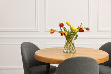 Vase with beautiful tulips on table in dining room