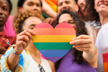 A group of LGBTQ people holding a rainbow heart celebrating International Pride Month.