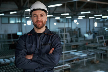 Handsome friendly guy. Factory worker is indoors with hard hat