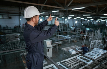 Gesture of thumb up. Factory worker is indoors with hard hat