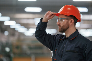Blurred background. Factory worker is indoors with hard hat