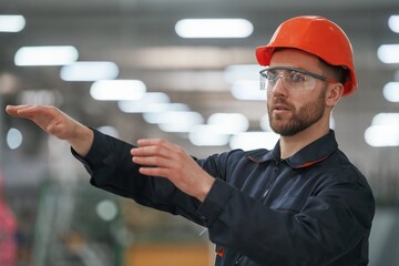 Busy employee. Factory worker is indoors with hard hat