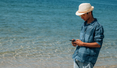 young man looking at his mobile phone on the beach