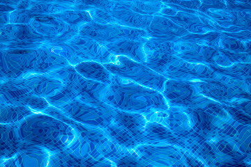 A close-up of the water in a swimming pool, with the sun shining through and creating a beautiful reflection.