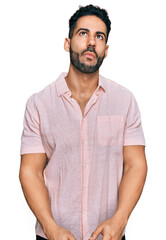 Hispanic man with beard wearing casual shirt making fish face with lips, crazy and comical gesture. funny expression.
