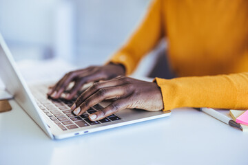 Black woman typing and browsing on a laptop in an office alone. African businesswoman doing research and planning on a laptop in an office alone. Cropped shot of an unrecognizable woman working 