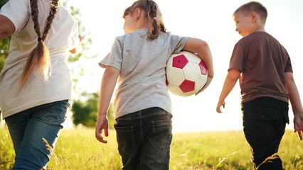 Children are walk in the park. A team of young athletes go to training with a ball game in the park. children walk carry ball and create a team. Games in the park. happy family kid dream concept fun - 767790771
