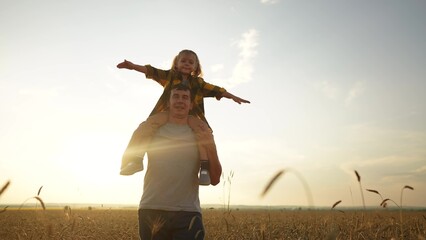 father and daughter in the park. happy family a behind his back walking in a wheat field...