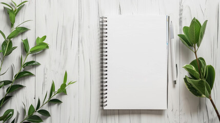 Blank notebook with pen and leaves on white wooden table. Space for text, flatlay, top view