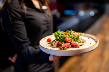 Person holding a plate of gourmet salad with seared tuna. The image captures the art of fine dining...