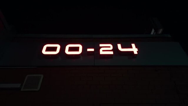 Large working time clock showing 00-24 on building wall in close-up view