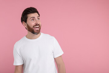 Portrait of happy surprised man on pink background, space for text