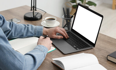 E-learning. Man using laptop during online lesson at table indoors, closeup