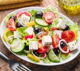 Greek salad on  wooden table served and ready to eat.