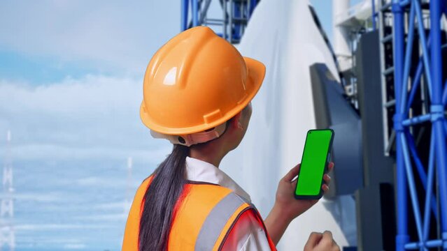Close Up Back View Of Asian Female Engineer With Safety Helmet Working On A Green Screen Smartphone And Looking Around With Space Shuttle