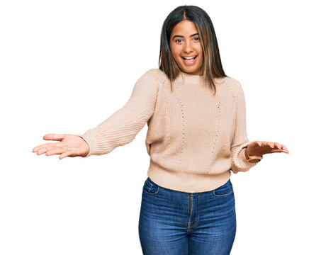 Young latin girl wearing wool winter sweater smiling cheerful offering hands giving assistance and acceptance.
