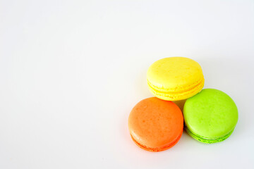 yellow, green and orange macarons on white background copy space 