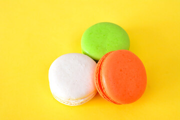 colorful macarons isolated on yellow background close up 