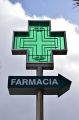 Illuminated Spanish 'Farmacia' Sign and Cross seen From Below Translated as Pharmacy 