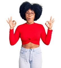 Young african american girl wearing casual clothes and glasses looking surprised and shocked doing...