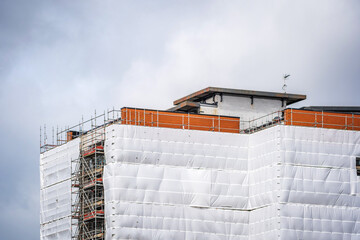 Flame retardant scaffold sheeting wrapped apartments building during insulation in england uk - obrazy, fototapety, plakaty