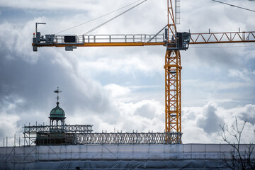Construction crane above flame retardant scaffold sheeting wrapped apartments building during insulation in england uk
