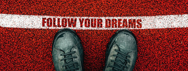 Follow your dreams text on rubber playground flooring, male boots from above standing next to the line - obrazy, fototapety, plakaty