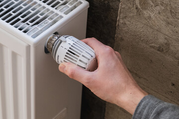 Hand adjusting temperature knob on a radiator