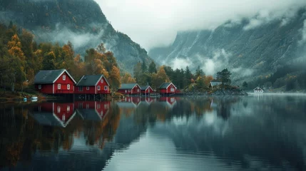 Fotobehang houses reflecting on a calm lake, surrounded by misty mountains © ORG