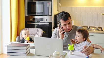 father working from home remotely with baby daughter in his arms. pandemic remote work business concept. father tries to work at home in kitchen, baby children interfere sitting on their hands fun - 767821790