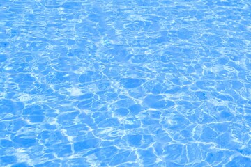 Blue water surface. Reflection of Sun in Water ripple surface texture. Blue clean water wave with splashes and bubbles. Natural summer banner background 