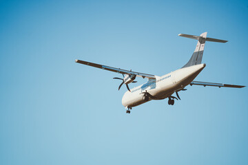 Rear view of an ATR 72 airplane in the clear blue sky. Twin-engine turboprop short-haul regional...
