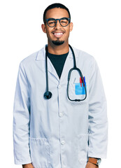 Young african american man wearing doctor uniform and stethoscope with a happy and cool smile on face. lucky person.