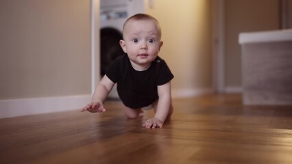baby learns to crawl on the floor at home. happy family kindergarten kids concept. First steps, baby crawling front view . baby learns to crawl to explore the world around dream him - 767824333