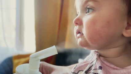baby breathes into an inhaler. baby has a respiratory disease breathes steam saturates the lungs with moisture. children medicine concept. baby with asthma close-up against of in a hospital lifestyle