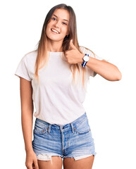 Fototapeta premium Beautiful caucasian woman wearing casual white tshirt doing happy thumbs up gesture with hand. approving expression looking at the camera showing success.
