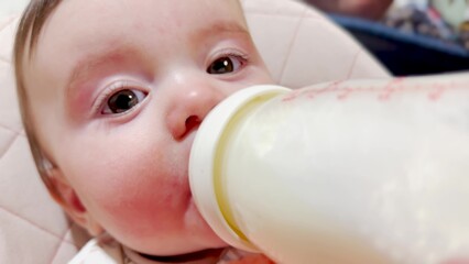 feeding a baby from a bottle. happy family kindergarten kid concept. first months of life. newborn baby enjoys milk. newborn baby enjoys milk. newborn baby drinks milk from a favorite bottle dream - 767827583