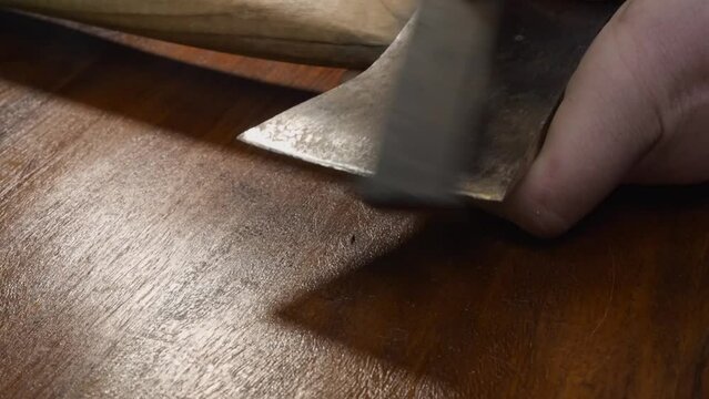 Old used axe head is made new again by sharpening edge with whetstone