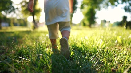 boy run in the forest park. close-up child legs run on the park green grass in the park. happy family childhood dream concept. a child in sneakers run on the grass in a park lifestyle - 767829946